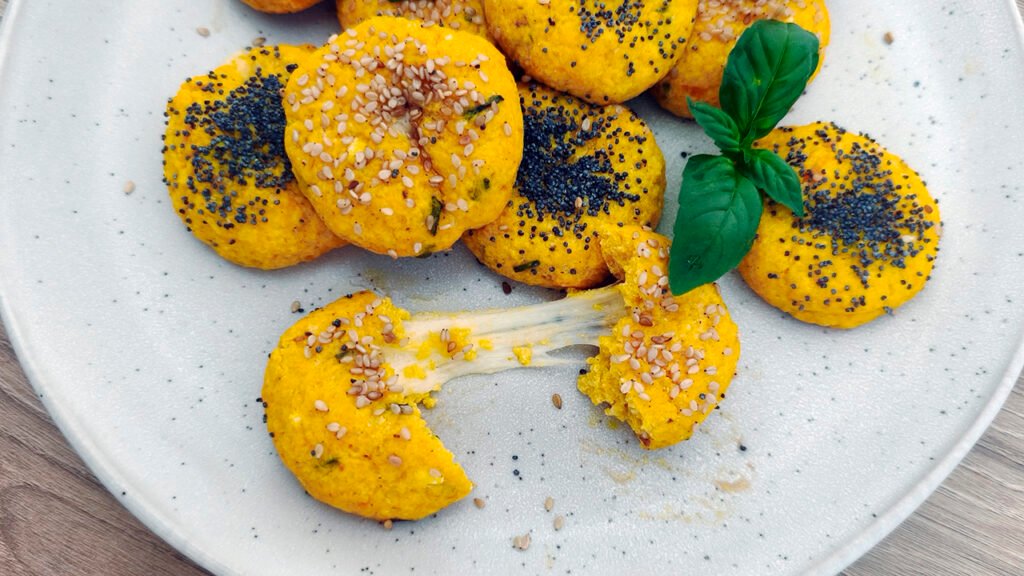 Polpette di zucca keto e senza glutine con semi di sesamo e papavero, servite su un piatto con basilico fresco